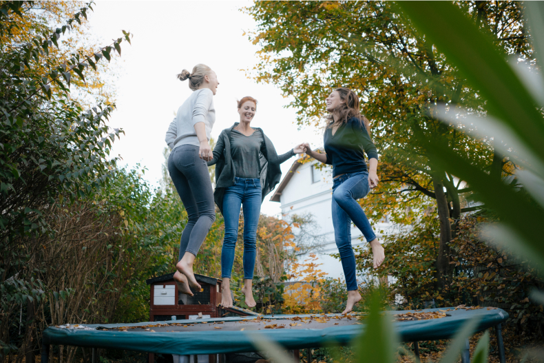 Drei Frauen auf einem Trampolin, das in einem Garten steht